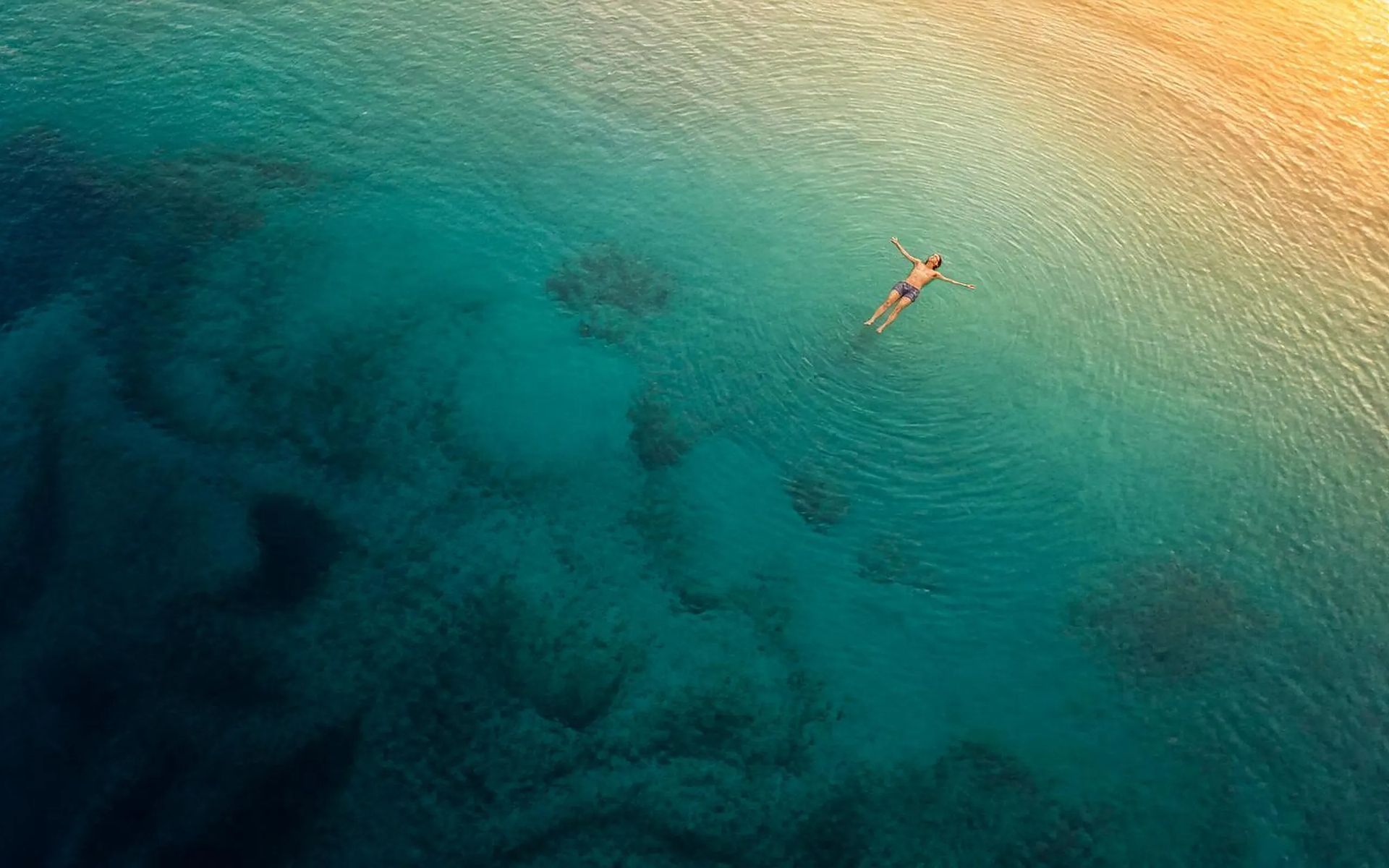 Una persona galleggia distesa in un mare calmo all’alba: un momento di ascolto di sé
